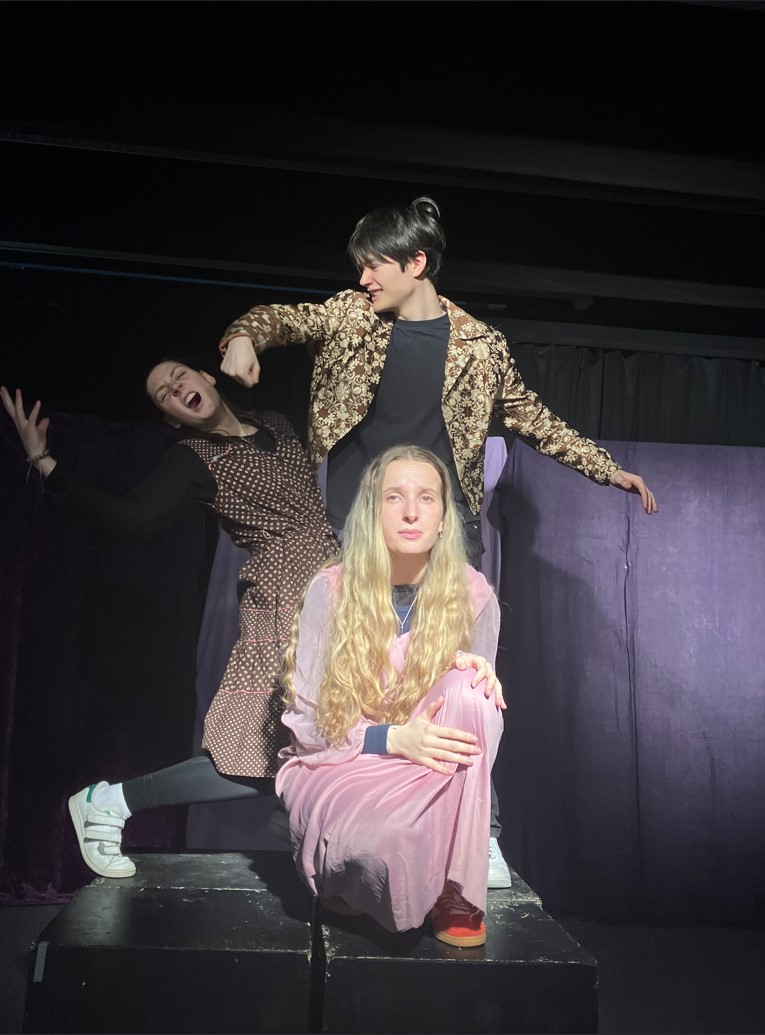 Drei Schülerinnen und Schüler spielen Theater. Sie posieren hintereinander.