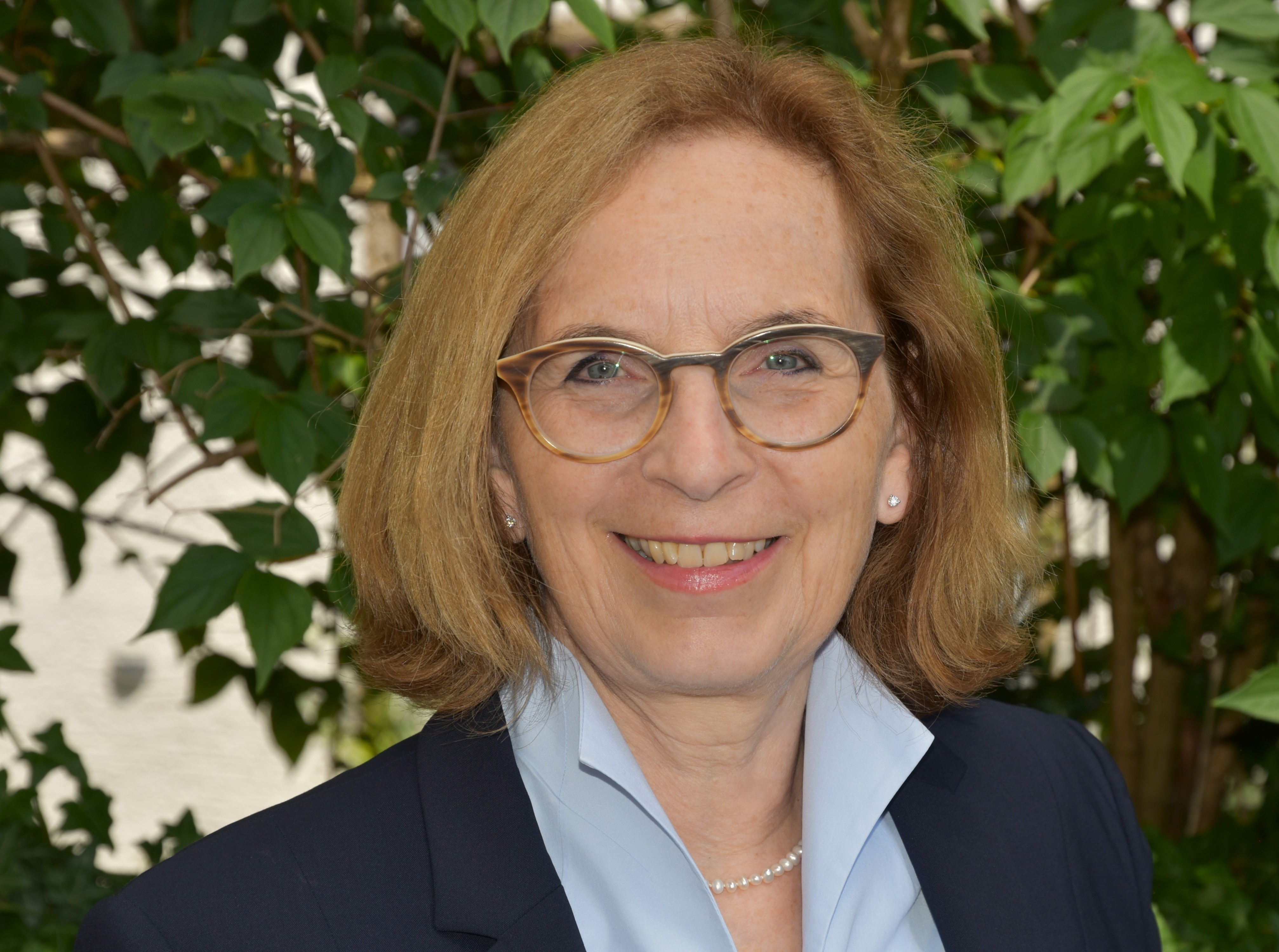 Porträt der Schulleiterin, aufgenommen vor einem blauen Hintergrund.